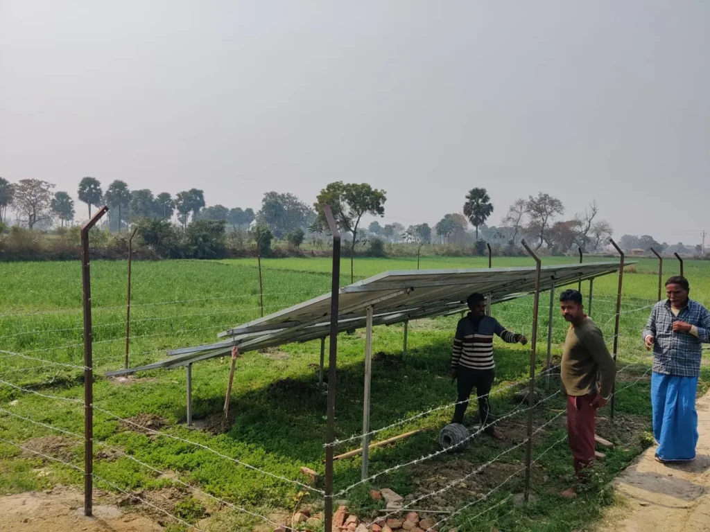 Farmers standing near a newly installed solar panel array for sustainable irrigation, a key Natural Resource Management (NRM) & Climate Action initiative by BJUP in rural Bihar
