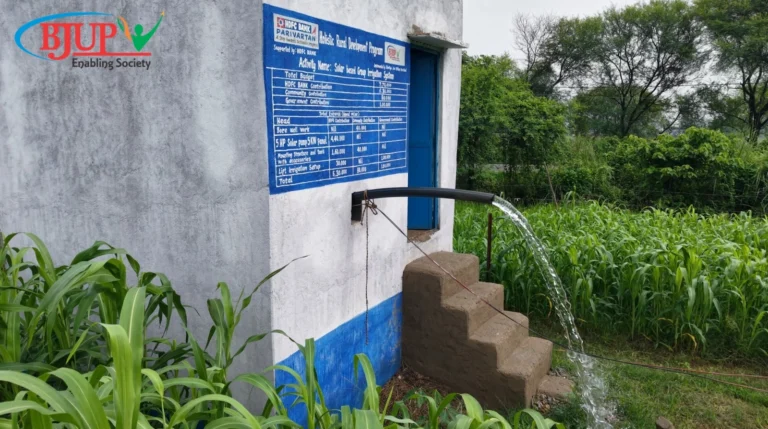 Water actively flowing from a solar-based group irrigation pump house into green fields, a successful CSR project by Climate-Resilient Agriculture NGO in Bihar BJUP and HDFC Bank Parivartan